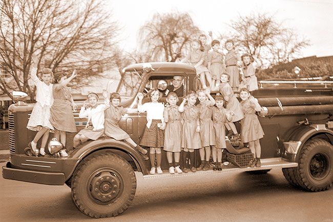 (January 8, 1958)##Grouped on a fire truck piloted by Chief Ivan Pearson, these Brownies are ready for a ride. They climbed aboard the truck during a tour of the fire station. Fifteen members of the group and one guest were taken on the tour by their leader, Mrs. Rex Haynie. The Memorial School second grade group is a new troop started last October. Co-leaders are Mrs. Russel Neuman and Mrs. R.C. Elofson.