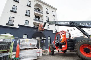 Marcus Larson / News-Register##Using a techhandler, construction workers lift new furniture up to the second floor of the Atticus Hotel. The boutique hotel is scheduled to open April 1, along with BYH Burgers on the ground floor, which is hosting a burger party and job fair Sunday.