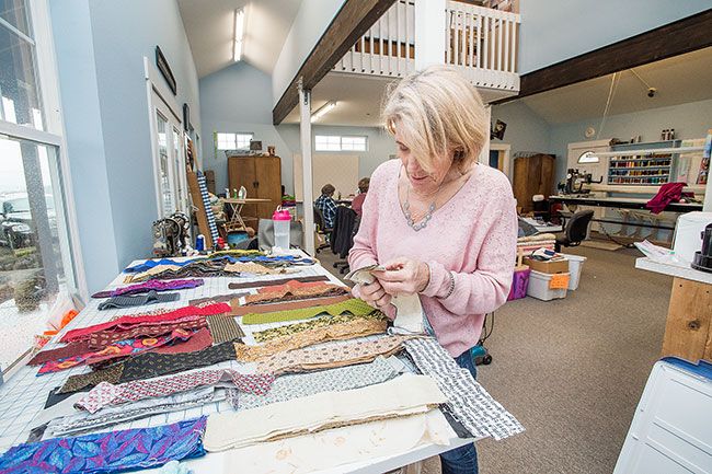 Marcus Larson/News-Register##Susan Boyd sorts through fabric strips of different colors and patterns during a Quilts for Cops work party. The nonprofit program primarily uses muted colors, blues, grays and greens in its quilts.