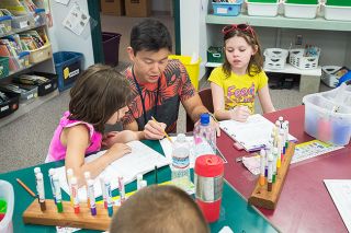 Marcus Larson/News-Register##Columbus second-grade teacher Reid Kimura helps students Alyse Waldron and Sarah Leggett in April 2013, just after Kimura was named “Outstanding Young Educator.” Marcus Larson/News-Register##Columbus second-grade teacher Reid Kimura helps students Alyse Waldron and Sarah Leggett in April 2013, just after Kimura was named “Outstanding Young Educator.”