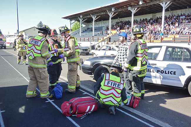 Starla Pointer / News-Register##As community members and students watch from the grandstand, medics assist a  victim  of the mock crash Friday morning.