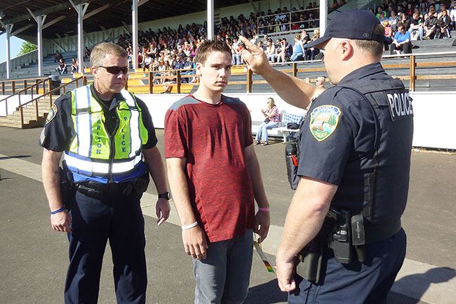 Starla Pointer / News-Register##Yamhill police officer Tom Hoy, right, and Carlton officer Robert Anderson administer a drunk driving test to student actor Cody Almond, who was playing the role of a drunk driver. The mock crash is made to seem as real as possible in order to hammer home the message about the dangers of drunk driving.