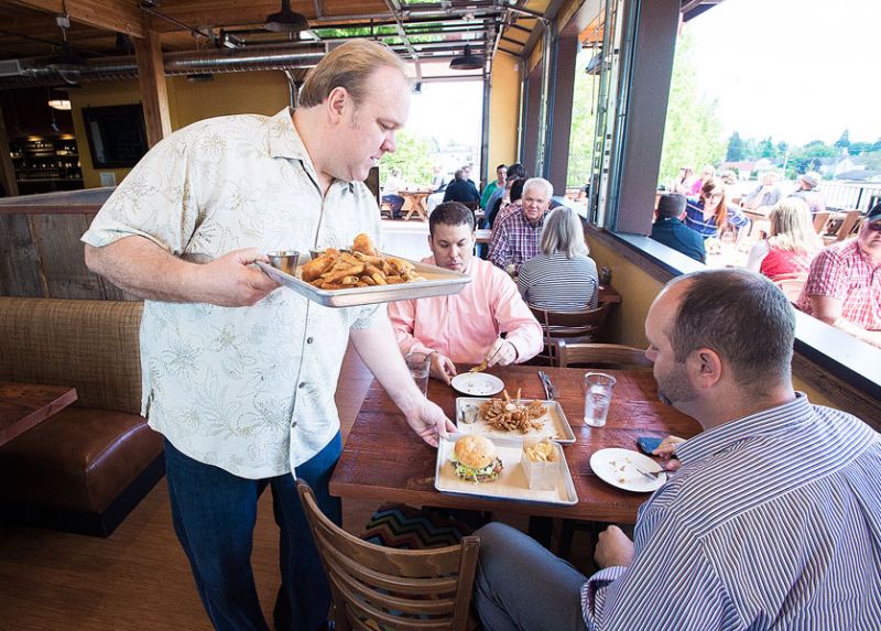 Marcus Larson/News-Register##Owner of the newly opened 1882 Grille, Dustin Wyant, helps serve food to
customers during a busy opening day.