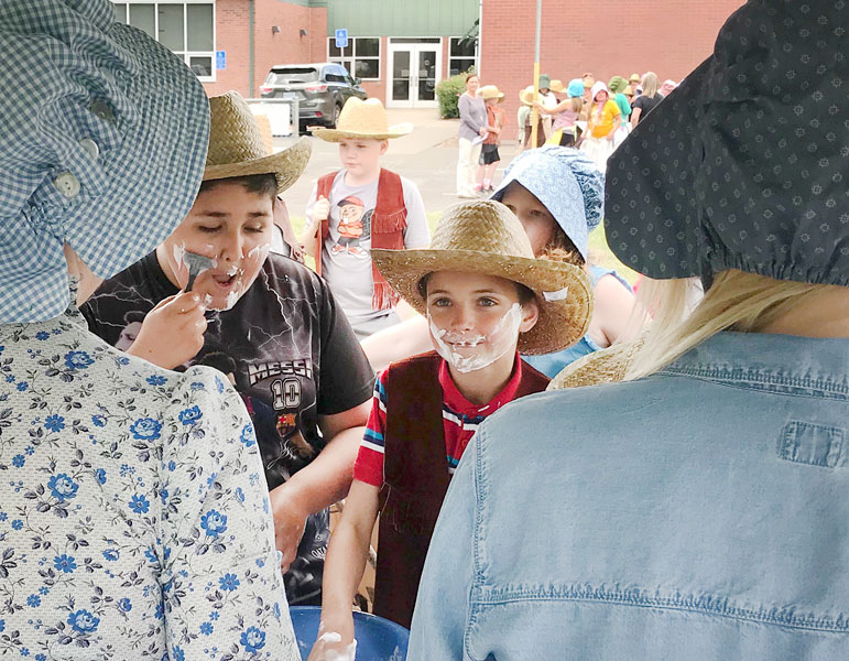 Heather Brooks/News-Register##Memorial Elementary students Benjamin Gudino (left) and Ezekiel Headings hit the first stop on the trail to prepare for the journey and chose to spend some of their money on a shave.