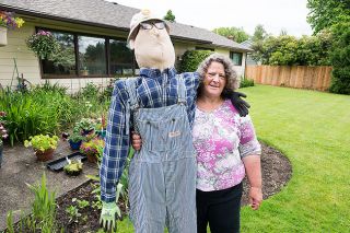 Marcus Larson/News-Register##Rhonda Robins poses with the friendly scarecrow she made to resemble her dad, Milt Robins, who loved to garden. His overalls, shirt and glasses adorn the scarecrow. Marcus Larson/News-Register##Rhonda Robins poses with the friendly scarecrow she made to resemble her dad, Milt Robins, who loved to garden. His overalls, shirt and glasses adorn the scarecrow.