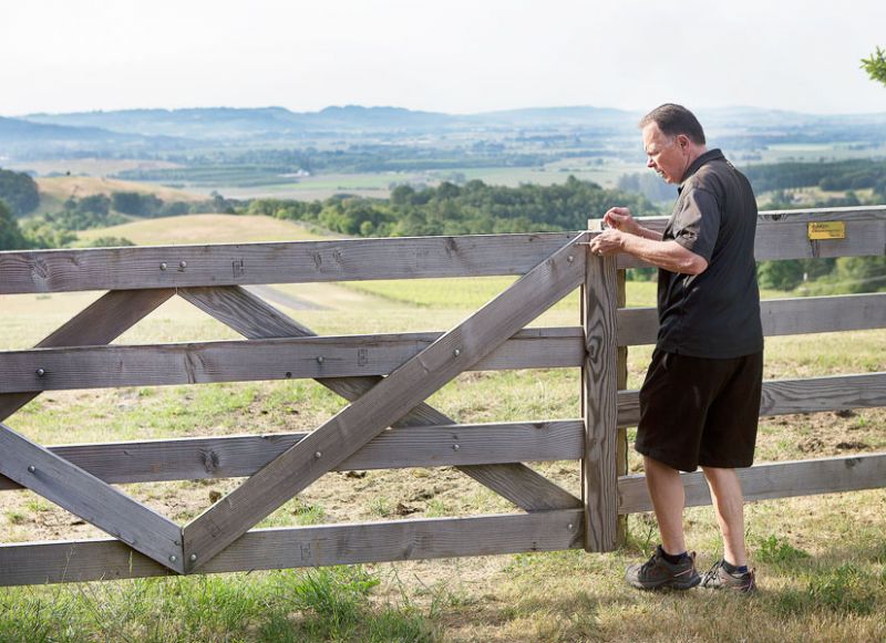 Rockne Roll/News-Register##Bailey opens the gate to the cow pasture on his property. Bailey grew up on a farm, where his family grew corn, oats and other crops, and raised livestock.