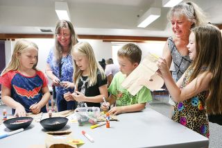 Rockne Roll/News-Register##Aubrey Lynch, 8, shows her artistic creation to her grandmother, Alisa Hoffman, as Nic Russell, 7, and Charlee and Rylee Perkins, both 8, work on their projects with librarian Nicki Hardee. The kids were making hand puppets inspired by Scaredy Squirrel, the title character in Melanie Watt’s book series. Rockne Roll/News-Register##Aubrey Lynch, 8, shows her artistic creation to her grandmother, Alisa Hoffman, as Nic Russell, 7, and Charlee and Rylee Perkins, both 8, work on their projects with librarian Nicki Hardee. The kids were making hand puppets inspired by Scaredy Squirrel, the title character in Melanie Watt’s book series.