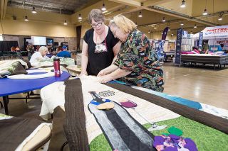 Marcus Larson/News-Register##Susan West and Elizabeth Hill check details on the wine country section of the tree skirt, which has “spokes” sewn to each side. The completed piece will be displayed in Washington, D.C. Marcus Larson/News-Register##Susan West and Elizabeth Hill check details on the wine country section of the tree skirt, which has “spokes” sewn to each side. The completed piece will be displayed in Washington, D.C.