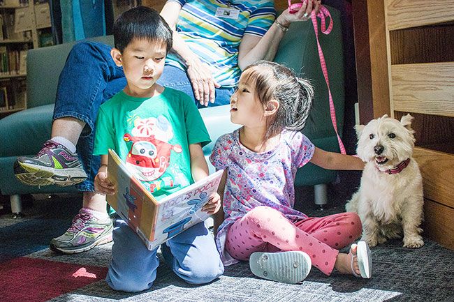 Anna Lieberman/ News-Register##
Siblings Michael, 7, and Claire Sun, 5, flip through a picture book, explaining the images to therapy dog, Summer. Both said they enjoyed spending time with the pup.