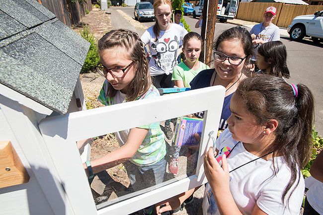Marcus Larson / News-Register##Student builders load books into one of the new little libraries.