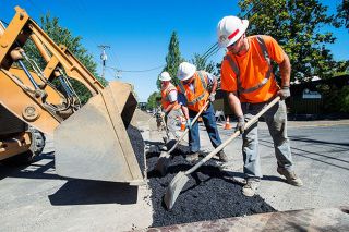 Marcus Larson/News-Register##After finishing laying a new water main connection line down fourth street, McMinnville Water & Light workers Ryan Sticka, Rolando Martinez, and Mark Knutz shovel hot asphalt to cover the portion across the intersection of 4th and Evans. Marcus Larson/News-Register##After finishing laying a new water main connection line down fourth street, McMinnville Water & Light workers Ryan Sticka, Rolando Martinez, and Mark Knutz shovel hot asphalt to cover the portion across the intersection of 4th and Evans.
