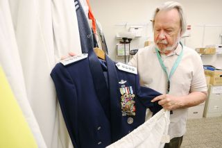 Rockne Roll/News-Register##Evergreen Aviation Museum Collection Manager Mickey Anderson pulls U.S. Air Force Gen. Merrill McPeak’s mess dress uniform from a protective bag. The museum plans a McPeak exhibit. Rockne Roll/News-Register##Evergreen Aviation Museum Collection Manager Mickey Anderson pulls U.S. Air Force Gen. Merrill McPeak’s mess dress uniform from a protective bag. The museum plans a McPeak exhibit.