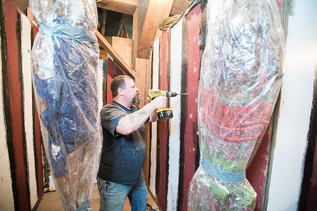 Marcus Larson/News-Register##Volunteer Todd Reed drills holes in the walls of one of the Haunted Granary’s “scare rooms.”