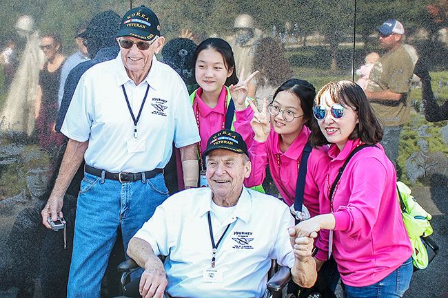 Submitted photo##Vronman, standing, and another Korean War veteran were viewing the monument to their war when they were surrounded by a crowd of young people visiting from South Korea. It turned out to be a youth choir.