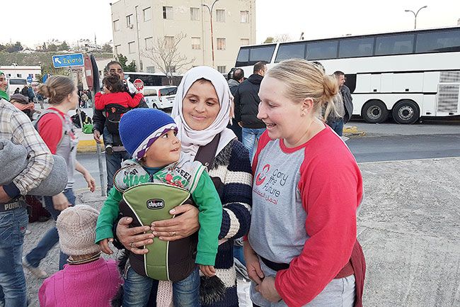 Submitted photo##Christine Anderson shares a smile with the toddler she just placed in a carrier. The McMinnville woman recently spent 10 days in Greece volunteering with the Carry the Future organization, which fits refugee parents with baby carriers to help ease their travels with young children.