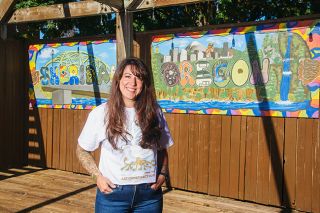 Rusty Rae/News-Register##McMinnville artist Natalie Fletcher stands before the two-panel mural created by eight students in the Art Conspiracy class. The work highlights the city of Sheridan and state of Oregon and is displayed in the Bridge Street plaza.