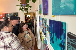 Kirby Neumann-Rea/News-Register##Art in the Parlor: Sabrina Lavos of McMinnville shows her paintings to her parents, Carran and Dan Lovas, at a pop-up art gallery Feb. 10 at Parlor Tattoo and Zen Gallery, 426 N.E. Third St., in downtown McMinnville. Co-owner Natalie Fletcher taught the week-long after-school art workshop and invited friends and family to the second-story business to view the teens’ artwork. “It was fun experimenting,” with a variety of techniques, said Sabrina, who has taken a variety of classes and looks forward to more. Fletcher said working with young people is a source of joy and plans future workshops. “It was as many people as we’ve had at one time up here,” said Fletcher, who in addition to body art, does murals and a wide range of works, including coordinating the McMinnville Downtown Association street corner paintings each June.