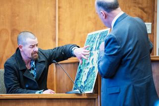 Rusty Rae/News-Register
Charles “Chris” Jones points out one of the pieces of property mentioned in testimony in the George Gebrayel murder-for-hire trial on March 6. Prosecuting attorney Colin Benson is holding the aerial image of the property.