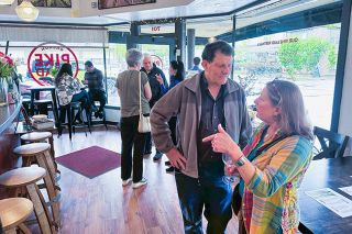 Kirby Neumann-Rea/News-Register##Nick Kristof talks with Joni Marten of Carlton, a Yamhill Carlton High School classmate, right, as Kristof and his wife, Sheryl WuDunn, center in background, greet visitors to the release of Kristof wines Friday at Pike Road.