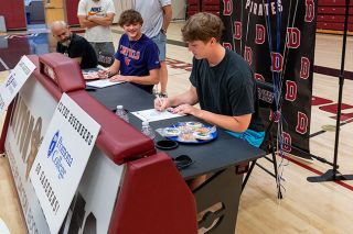 Rusty Rae/News-Register##Lane Garrison (left) and Clyde Rosenberg (right) sign their letters of intent to play at Linfield University and Pomona College, respectively, during a celebration inside the Dayton High School gymnasium. Rusty Rae/News-Register##Lane Garrison (left) and Clyde Rosenberg (right) sign their letters of intent to play at Linfield University and Pomona College, respectively, during a celebration inside the Dayton High School gymnasium.