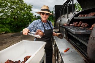 Rusty Rae/News-Register##Dressed in her vintage hat and dress, Ric Rac BBQ owner Shelby Wilcox removes slowly cooked meat from her huge smoker in preparation for a pop-up restaurant event. Wilcox cooks at The Preserve and offers catering. Her side dishes include recipes from all over the world, as well as traditional barbecue companions such as cornbread and greens. Rusty Rae/News-Register##Dressed in her vintage hat and dress, Ric Rac BBQ owner Shelby Wilcox removes slowly cooked meat from her huge smoker in preparation for a pop-up restaurant event. Wilcox cooks at The Preserve and offers catering. Her side dishes include recipes from all over the world, as well as traditional barbecue companions such as cornbread and greens.