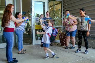 Rachel Thompson/News-Register##Owyn Bennett spins around in excitement as he leaves Buel Elementary School on his last day of first grade. With him are his mom, Kelsey, holding little brother Wali, and staff members blowing bubbles — from left, Koreena Petschauer, Laura Rivas, Kara Ecker and Emma Velazquez. Owyn said he’s excited about making art this summer and becoming a second-grader in the fall. Rachel Thompson/News-Register##Owyn Bennett spins around in excitement as he leaves Buel Elementary School on his last day of first grade. With him are his mom, Kelsey, holding little brother Wali, and staff members blowing bubbles — from left, Koreena Petschauer, Laura Rivas, Kara Ecker and Emma Velazquez. Owyn said he’s excited about making art this summer and becoming a second-grader in the fall.