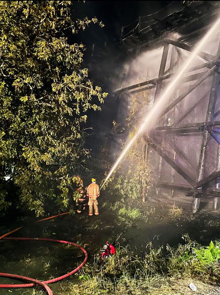 Tualatin Valley Fire & Rescue photos##Above: Firefighters continue to douse the trestle of an inactive rail line in Newberg Sunday morning. Below: A large section of the trestle is engulfed as crews arrive at the scene. Tualatin Valley Fire & Rescue photos##Above: Firefighters continue to douse the trestle of an inactive rail line in Newberg Sunday morning. Below: A large section of the trestle is engulfed as crews arrive at the scene.