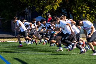 The Grizzlies run sprints on the Evans Street turf fields during the end of practice on Aug. 22. Coach Howard looks on in the background. ##Nathan Ecker/News-Register The Grizzlies run sprints on the Evans Street turf fields during the end of practice on Aug. 22. Coach Howard looks on in the background. ##Nathan Ecker/News-Register