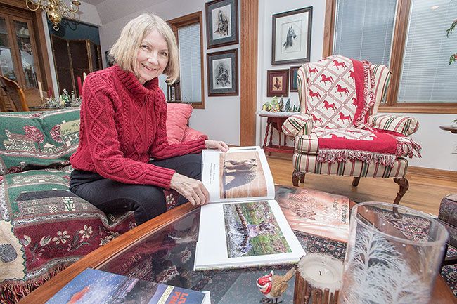 Marcus Larson/News-Register##Lou Ann Goodrich looks through her portfolio of finished pieces, which usually start with photos of wildlife. Goodrich is an animal lover who is concerned about the environment.