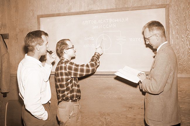 (December 30, 1957)##Field Emission diagram in Russian is studied by three staff members of Linfield Research Institute in a study of the Russian language. Twelve staff members have formed a class to study language so they will be able to read scientific material which has become available from that country, during the past year. Several wives of LRI staffers, Dr. Helen Emerson of the Linfield Modern Language Department, and Mrs. Elizabeth Honn of McMinnville High School also are enrolled in the course. Shown examining the diagram are, from left, Phil Bettler, staff physicist; Frank Collins, supervisor of the LRl Glass Laboratory, and W. W. Dolan, LRI assistant director.