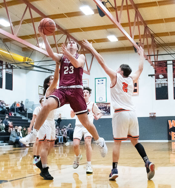 Rusty Rae/News-Register##
Dayton senior forward Tyler Spinks sails in for a lay-in during the Pirates contest against Willamina Wednesday night. Defending on the play is Willamina’s Kaleb Cruickshank. Spink finished the game with 12 points.