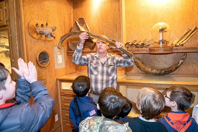 Rusty Rae/News-Register##
Fossil hunter Mike Full of McMinnville, part of the Willamette Valley Pleistocene Project, holds up petrified mammoth bones for members of Cub Scout Pack 470 to see. More bones from ancient creatures are on display behind him. Scouts visited the fossil room Monday and helped stabilize some of the newest finds.