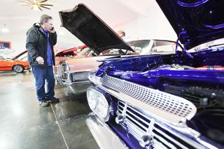 Rockne Roll/News-Register##Joel McKaig of American Classics and Hot Rods discusses a 1965 Cadillac DeVille with a customer by phone. The business is located on First Street in Newberg.