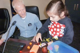 Starla Pointer / News-Register##
As school board member Paul Haddeland observes, Adalynn Lauber chooses materials that will conduct electricity. When the Newby student holds the items, the flow of current will cause a computer to play a musical note. Starla Pointer / News-Register##
As school board member Paul Haddeland observes, Adalynn Lauber chooses materials that will conduct electricity. When the Newby student holds the items, the flow of current will cause a computer to play a musical note.
