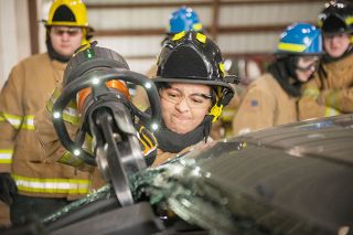 Rusty Rae/News-Register
##
McMinnville High School firefighting skills student Angeles Ceja uses a hydraulic cutting tool to snap the post holding up the rear driver s side of the roof of the wrecked sedan. The tool is heavy, she said, but she learned techniques that let her control it.