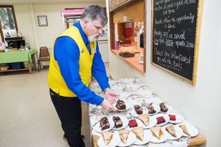 Marcus Larson/News-Register##Dennis Esplin, a longtime volunteer for The Soup Kitchen at St. Barnabas, prepares the dessert table with assorted pies and the day’s special, chocolate cake with caramel.