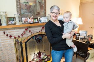 Marcus Larson/News-Register ## 
In her McMinnville home, avid repurposer Ann Austin poses for a portrait with her grandson, 9-month-old Milo Nelson. He is the fifth generation to sleep on her great-grandparents’ bed, which she treasures.