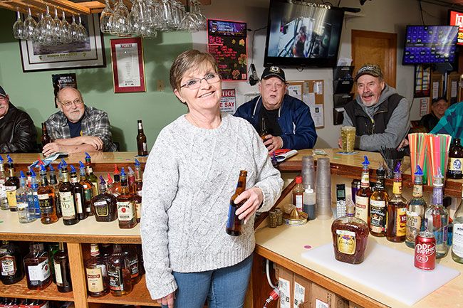 Rusty Rae/News-Register##Legion Auxiliary State President Debra Godwin is always smiling whether she’s serving up a beer from behind the bar at the McMinnville American Legion Vets Club or delivering a meal to a patron. Like
staff at the TV bar Cheers, the volunteer knows everybody’s name — including the three joking with her in the background, from the left, John Kovach, Rich Pimm and Al Schmidt.