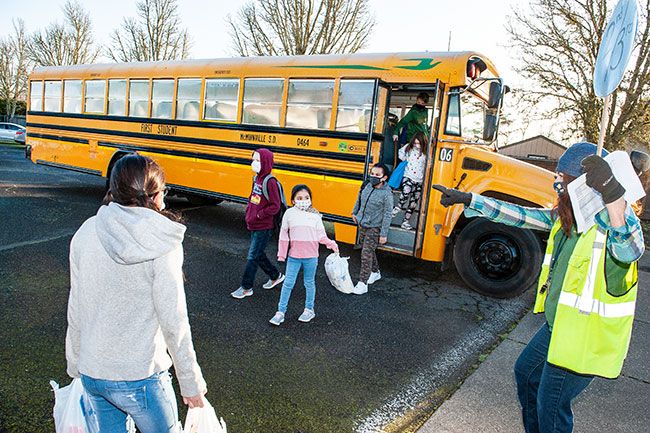 Rusty Rae/News-Register ##
Reading instructor Megan Whitaker points the way to students as they hop off the bus and head back to classes at Columbus Elementary School Monday morning, the first day of hybrid learning in the McMinnville School District.