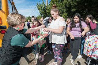 Rusty Rae/News-Register##Sue Buel Elementary kitchen manager Karin Nichols takes food service on the road Tuesday, handing out lunches and breakfasts for children at a bus stop along Highway 18.
