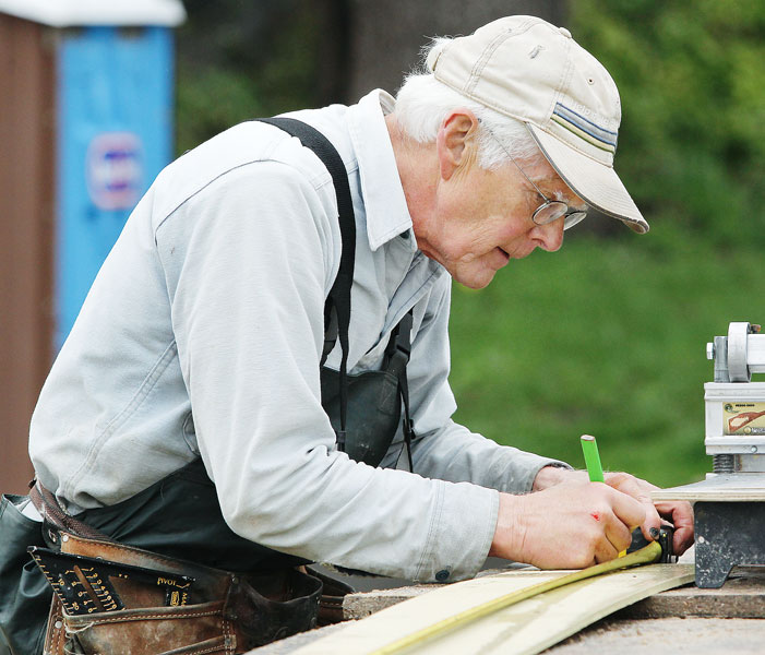 Rockne Roll/News-Register##Cruikshank marks a section of siding before cutting. His friend and fellow volunteer Cliff Probasco taught him to do things right on the job site — such as “measure twice, cut once.”