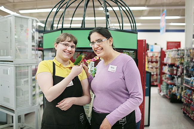 Submitted photo##MV Advancements client Rene Dominic, right, poses with her coworker Leah Baker and Lilly the bird at the McMinnville Petco store.