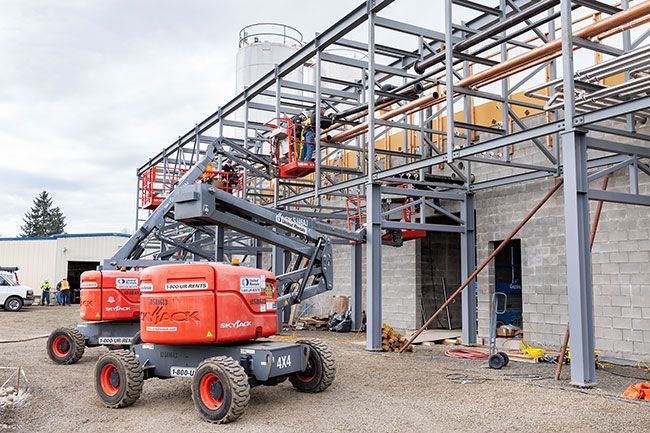 Marcus Larson/News-Register ##  Construction workers lay new piping along a steel beam lattice structure that will carry milk products around the rebuilt plant.