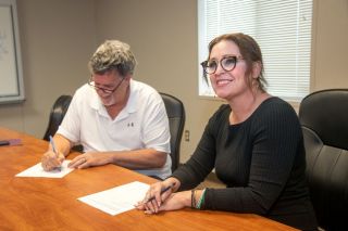 Rusty Rae/News-Register##Dayton School Board Chairman Larry Ringnalda signs a contract with Amy Fast, Dayton’s new school superintendent, in a ceremony Monday. Fast, now principal of McMinnville High School, will replace Dayton’s Steve Sugg, who is retiring in June.