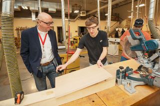 Rusty Rae/News-Register##School board Chairman Carson Benner visits with Spencer Stritzke, who is building a TV cabinet in the wood shop at McMinnville High School. Benner visited construction and other pathway programs at Mac High last month.