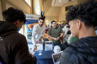Rachel Thompson/News-Register##LatinoBuilt employees Jose Rico and Luis Morales engage with participants of the Mente Summit career fair at Linfield University. The company assists Latino contractors in Oregon.