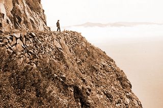 Image: UO Libraries ## A man stands on the roadbed cut into the face of Neahkahnie Mountain in the 1930s.
