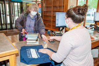 Rusty Rae/News-Register ## Judith Pasch hands her library card to librarian Katie Thompson as she checks out a stack of books at the McMinnville Public Library on Saturday.
