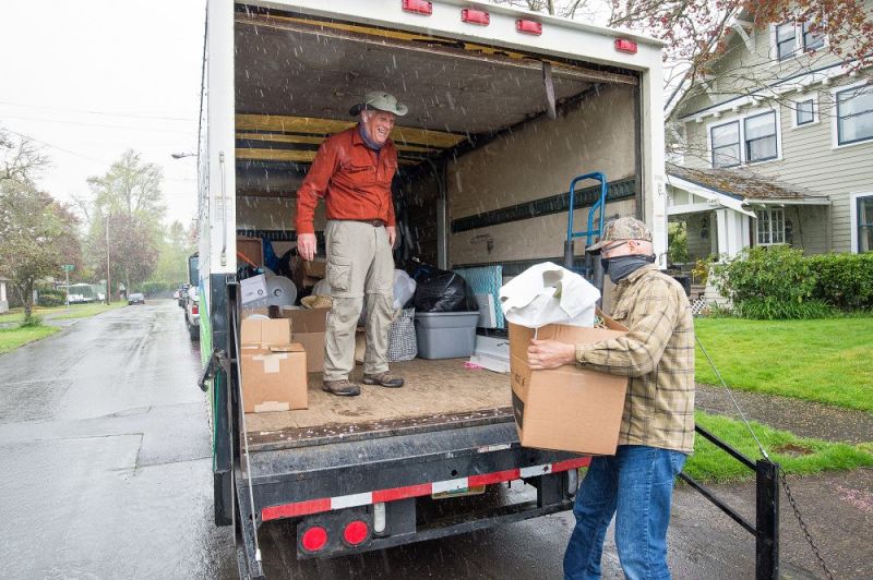 Marcus Larson/News-Register##Volunteers Ron Noble, right, and Greg Smith load donated items into a Habitat for Humanity ReStore truck during a curbside pickup.