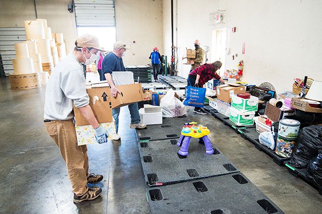 Marcus Larson/News-Register## Aidan Nyquist and other volunteers place collected donations on pallets for storage. Items will be given away to local charities or sold online to raise funds for local nonprofits.